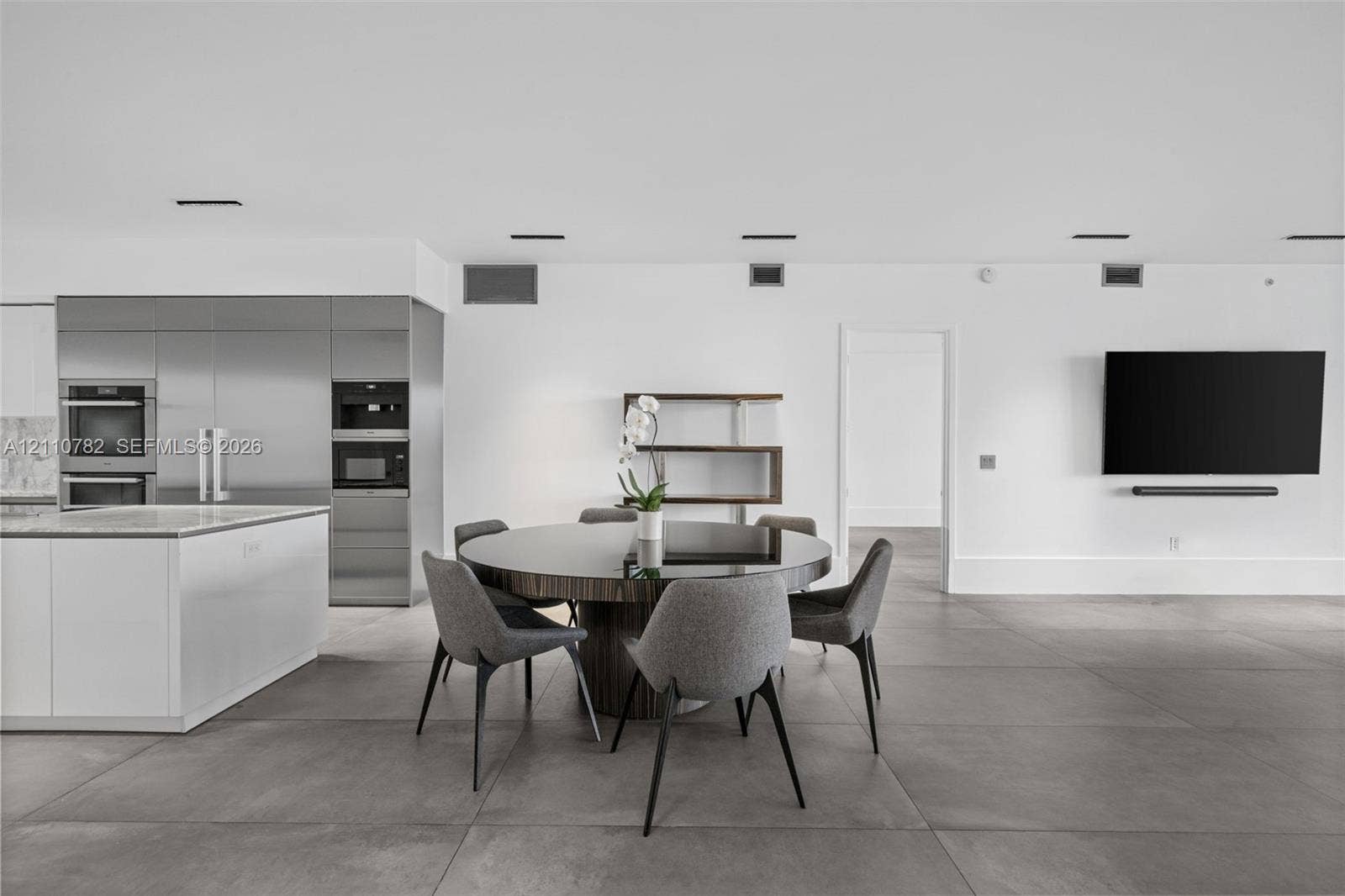 Open-concept space featuring large-format tile flooring, stainless steel integrated appliance suite, built-in shelving, and recessed ceiling lighting