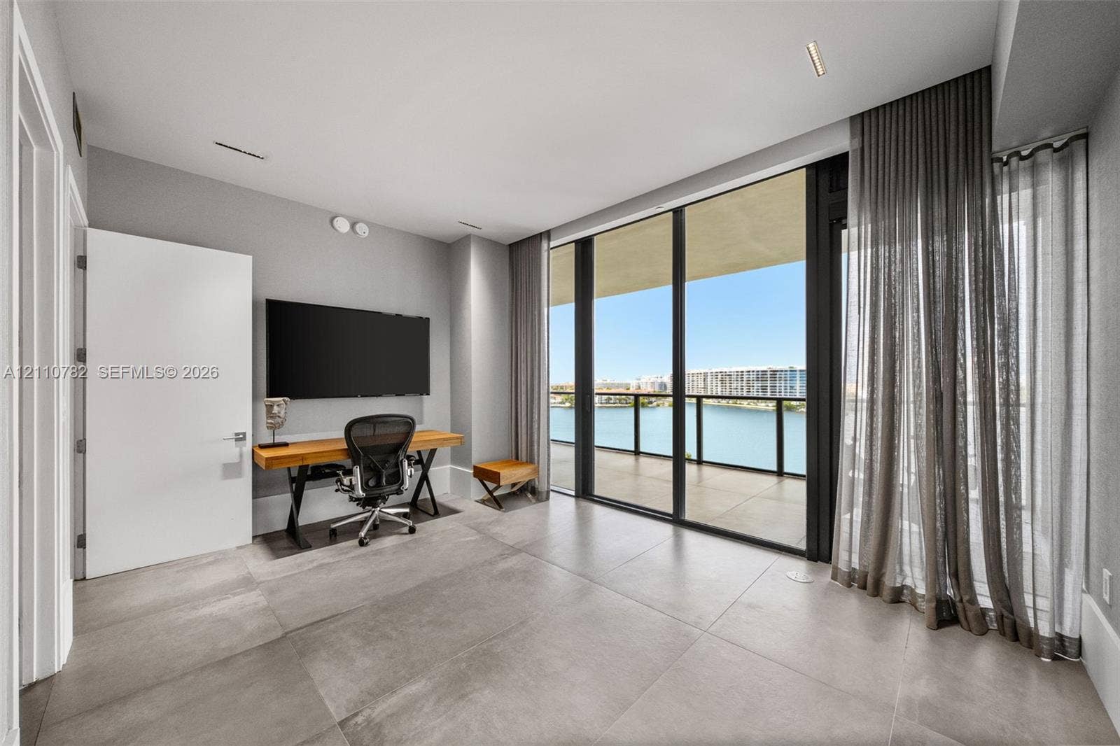 Floor-to-ceiling glass wall, large-format tile flooring, recessed ceiling lighting, and covered balcony featuring a glass panel railing