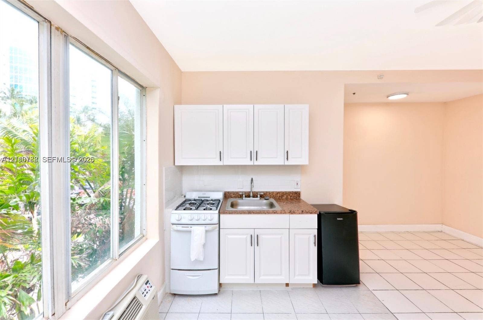 3710 Collins Avenue, #N-202, Miami Beach, FL 33140 Kitchenette featuring white cabinetry, stone-finish countertops, stainless steel sink with metal faucet, gas range, and tile flooring