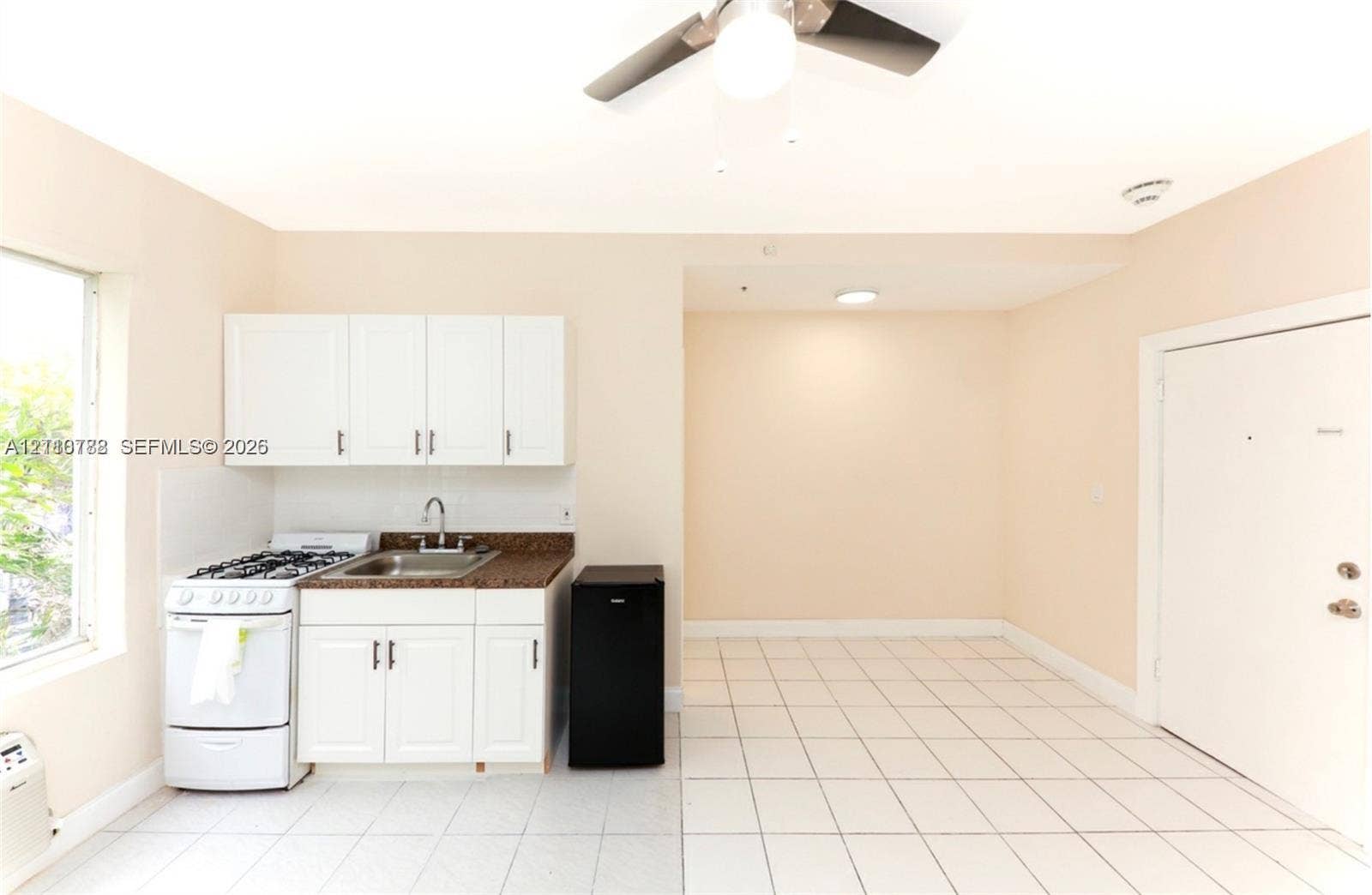 3710 Collins Avenue, #N-202, Miami Beach, FL 33140 Kitchenette featuring white cabinetry, stone-finish countertops, stainless steel sink with gooseneck faucet, gas range, and tile flooring