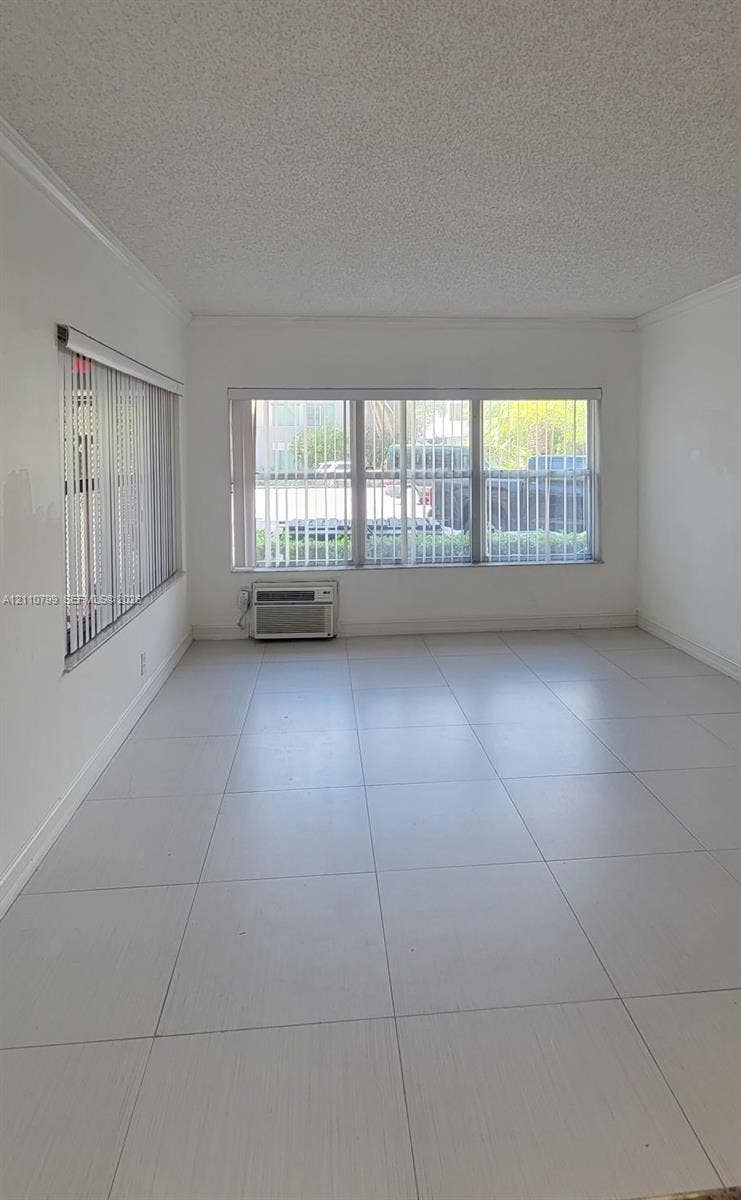 Light-filled room featuring neutral large-format tile flooring, textured ceilings, and expansive multi-pane windows with vertical blinds
