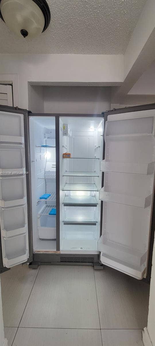 Stainless steel side-by-side refrigerator featuring adjustable glass shelving, clear storage drawers, and integrated door bins