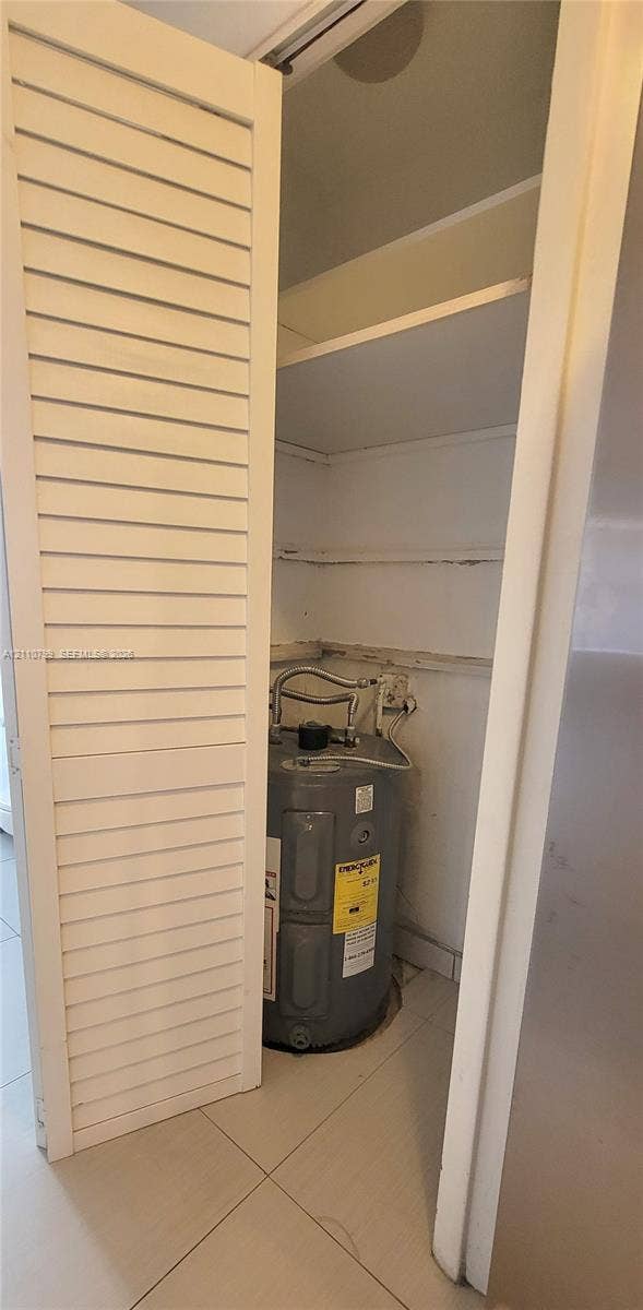 Utility closet featuring louvered bi-fold doors, tile flooring, and integrated white shelving