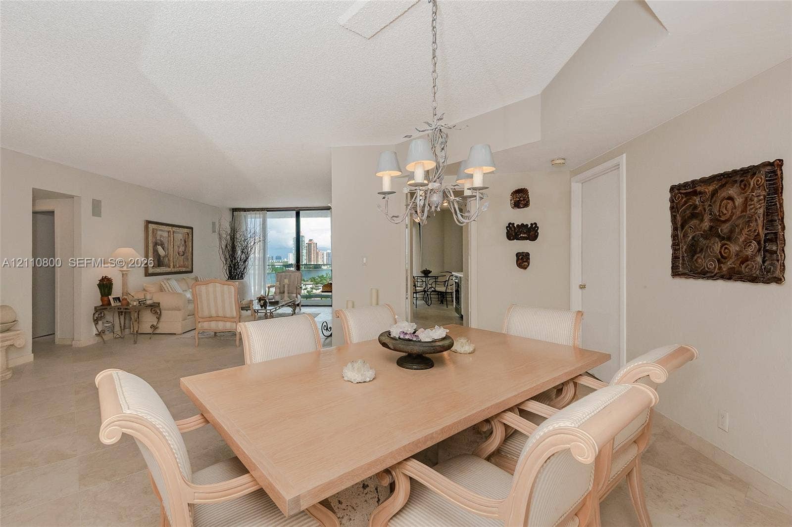 Dining area featuring stone-finish tile flooring, a multi-arm decorative chandelier, and a vaulted ceiling