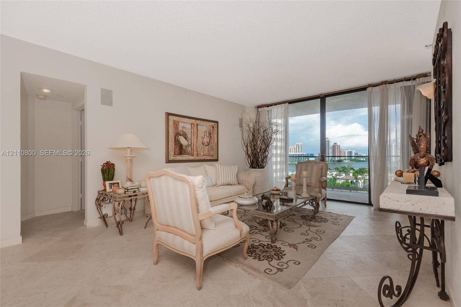 Living area featuring large-format tile flooring and floor-to-ceiling glass sliding doors opening to a balcony