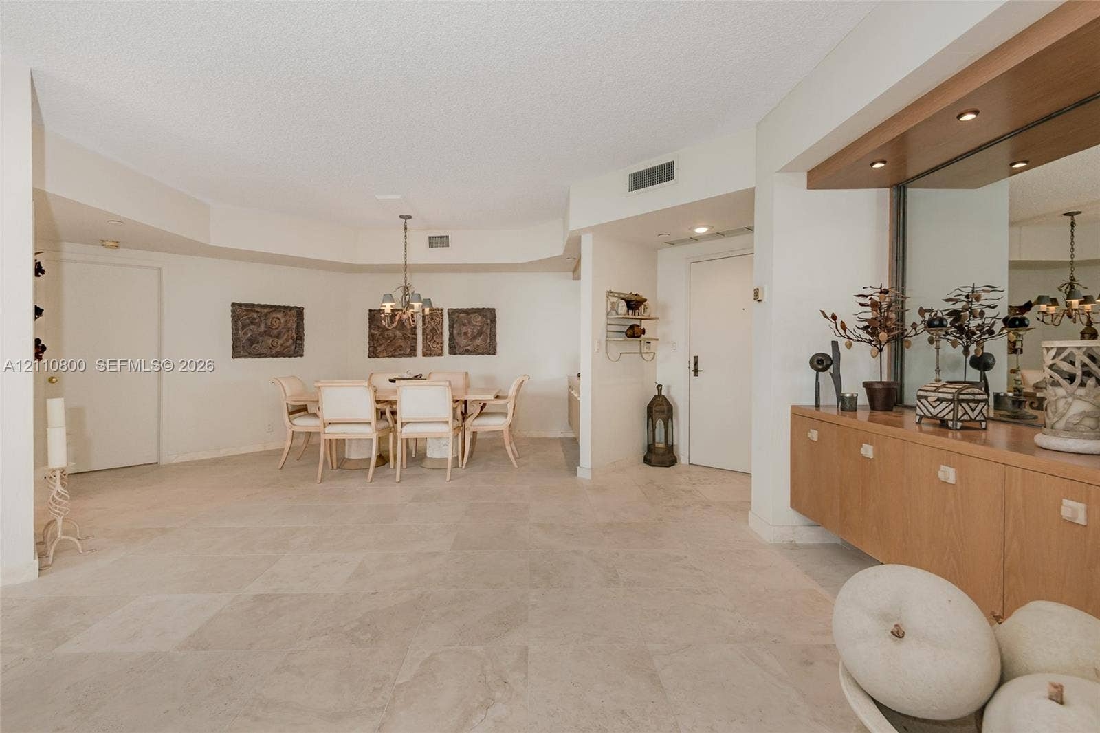 Large-format stone tile flooring, built-in wooden cabinetry with mirrored backsplash, and recessed lighting