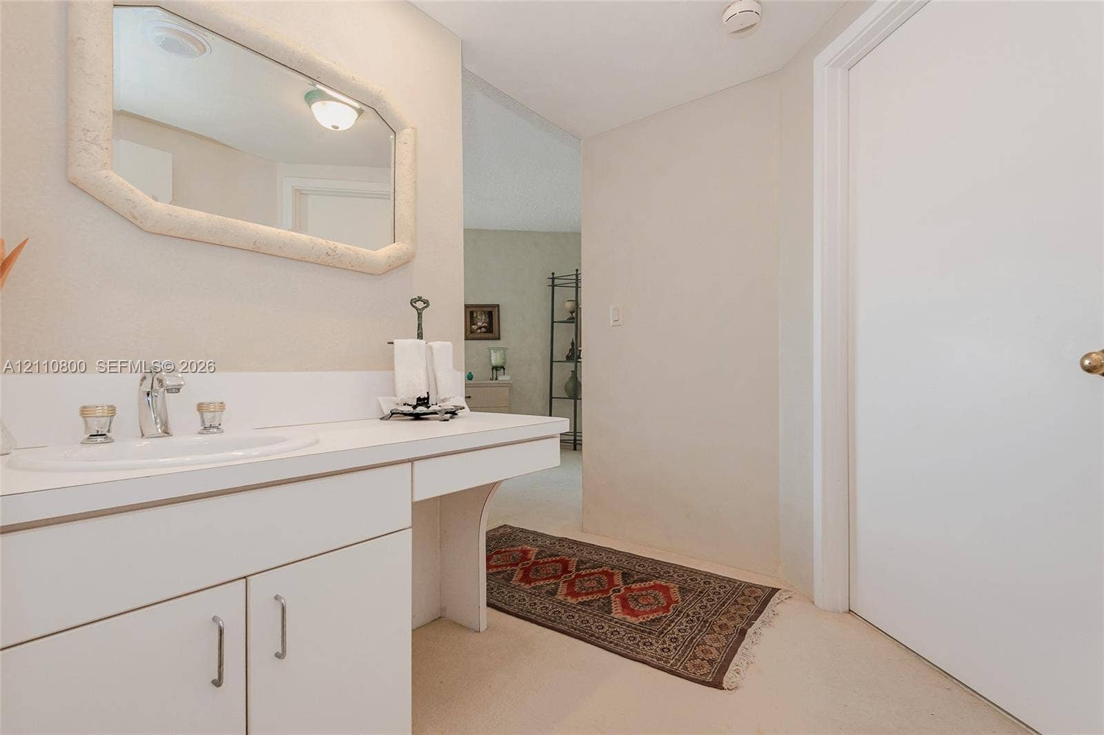 Built-in white cabinetry with a surface-mounted vanity sink, polished chrome faucet, and framed wall mirror