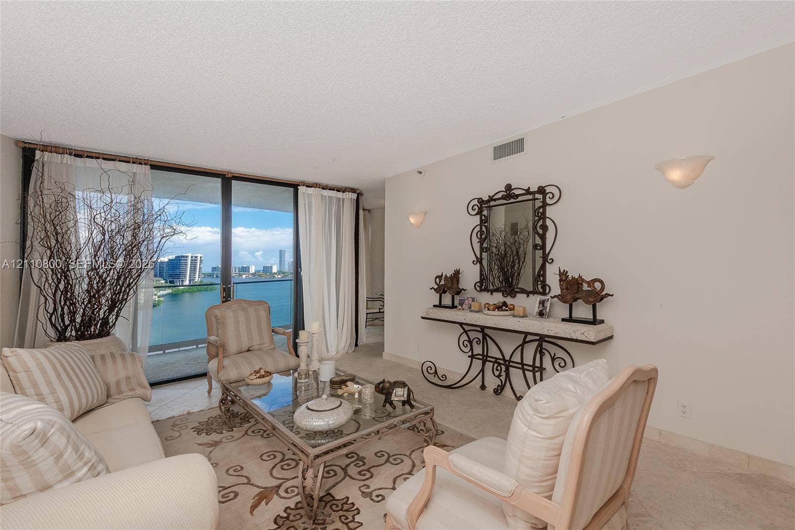 Floor-to-ceiling sliding glass doors, neutral stone-finish tile flooring, and wall-mounted sconce lighting