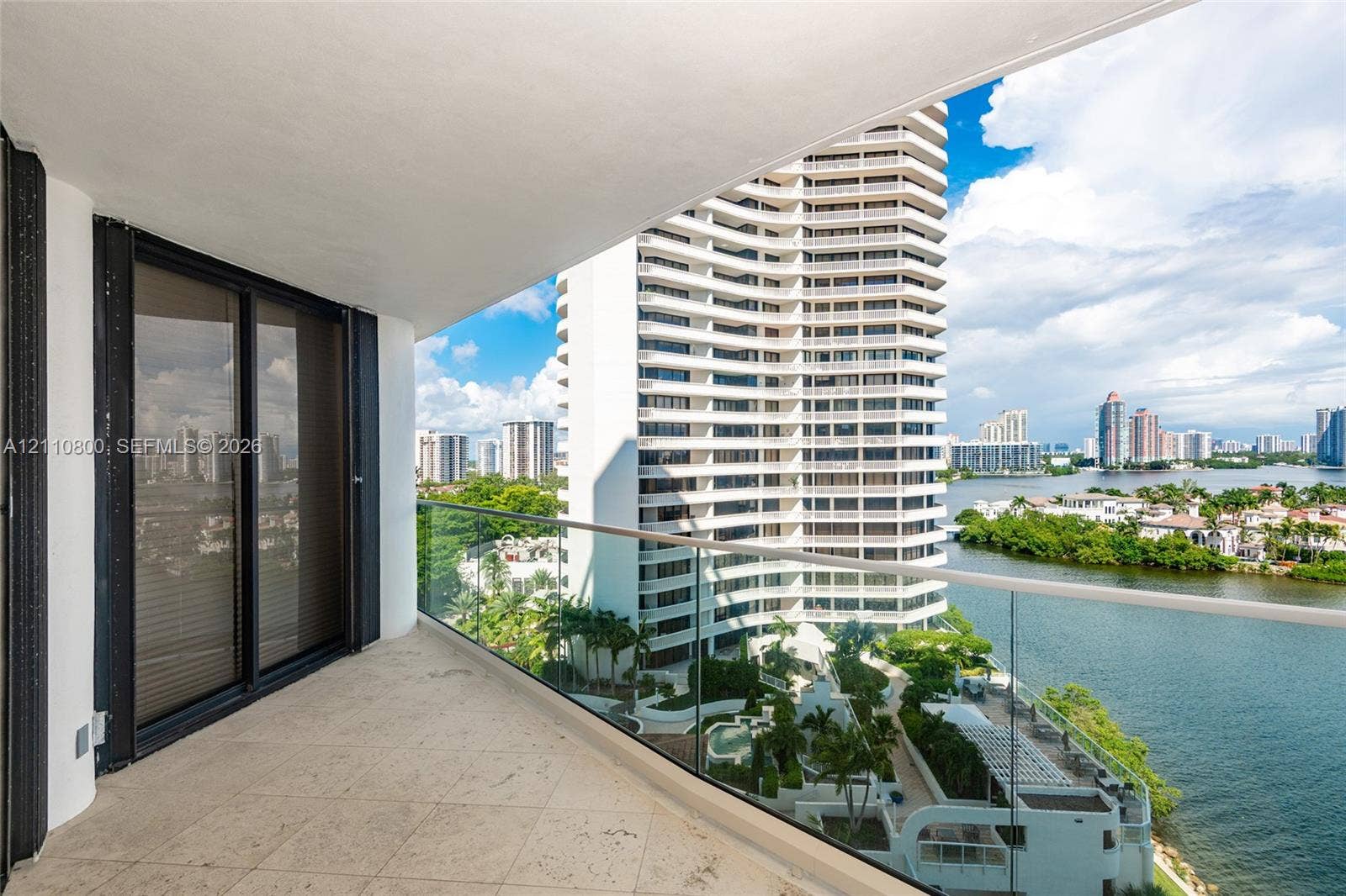 Covered balcony featuring tile flooring and a frameless glass railing