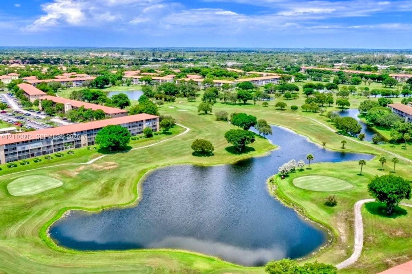 Aerial perspective of multi-unit residential structures overlooking expansive golf course grounds featuring manicured fairways, water hazards, and mature landscaping