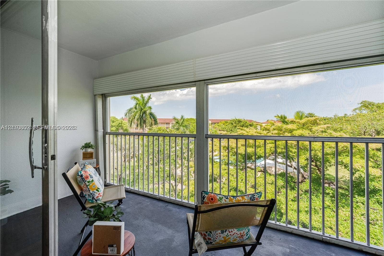Enclosed balcony featuring floor-to-ceiling sliding glass doors, metal railing, and retractable horizontal blinds