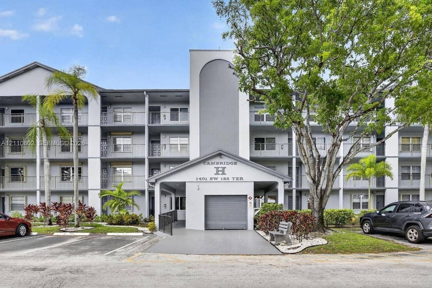 Multi-story exterior building featuring a covered entryway, private balconies, and mature landscaping