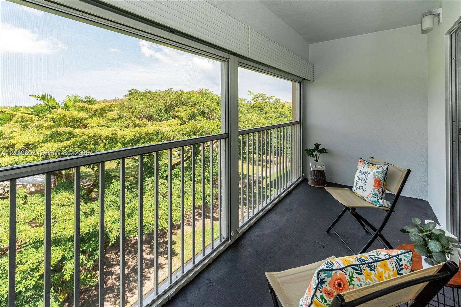 Covered balcony featuring metal railings, sliding glass window panels, and wall-mounted lighting