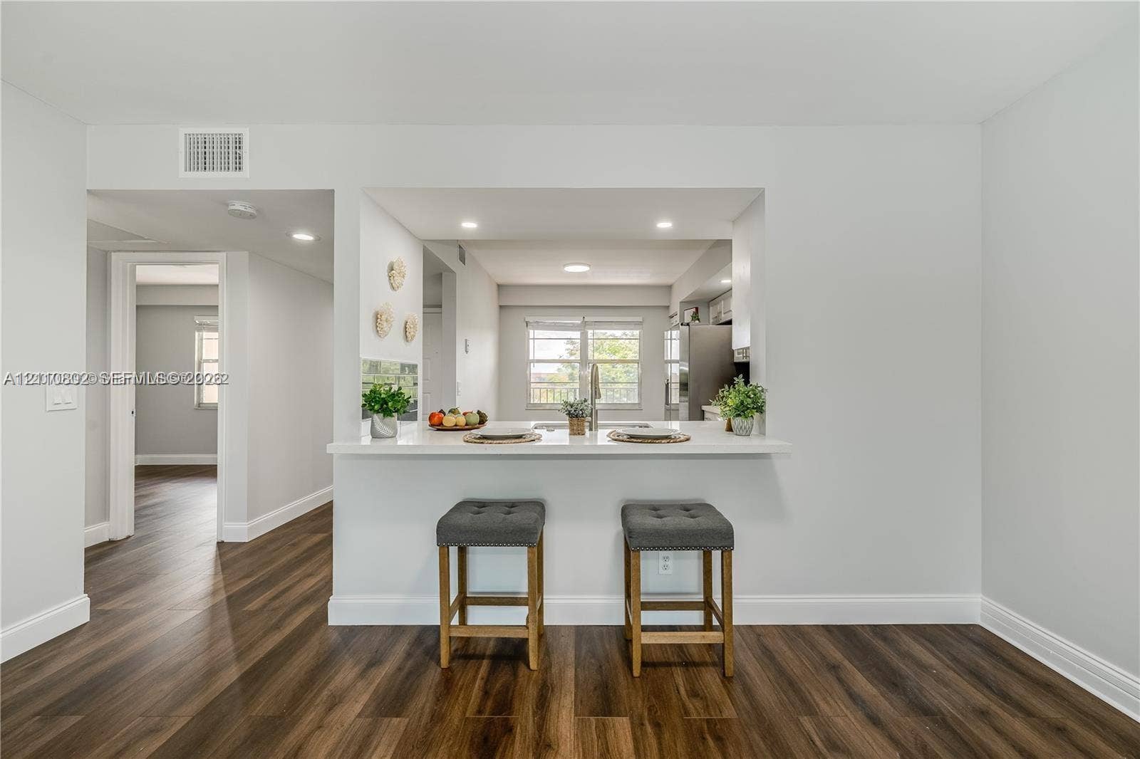 Kitchen featuring an open pass-through window with a quartz countertop breakfast bar, recessed lighting, and wood-finish flooring