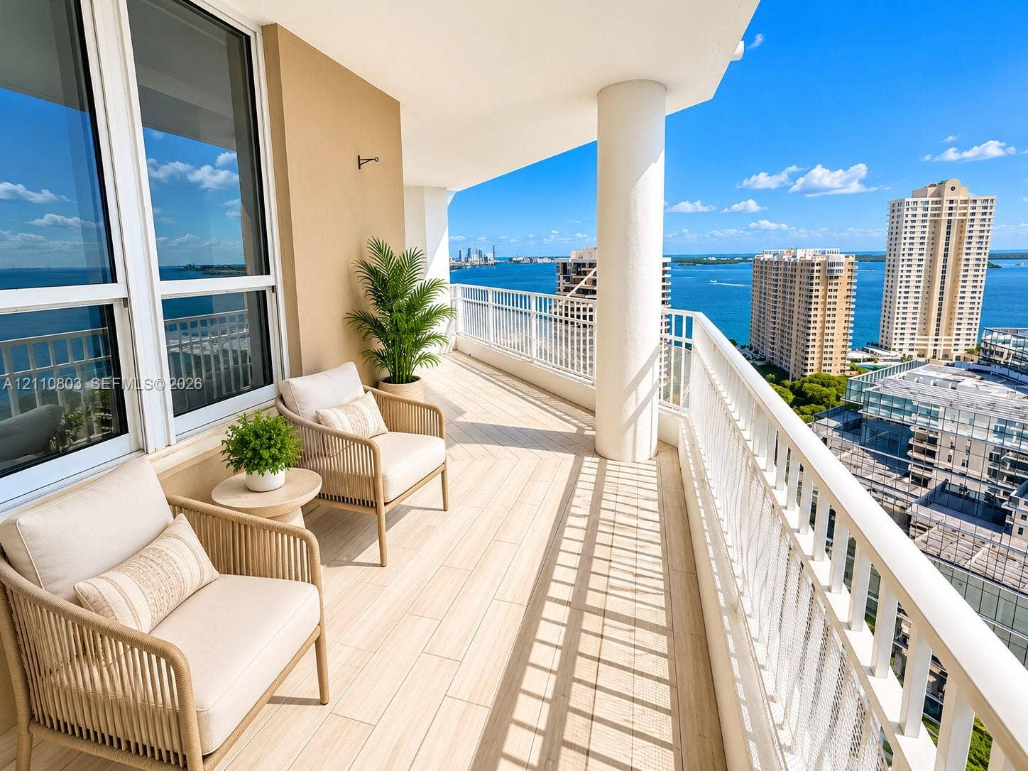 Covered balcony featuring wood-finish tile flooring, white metal railing, and expansive water and urban skyline scenery