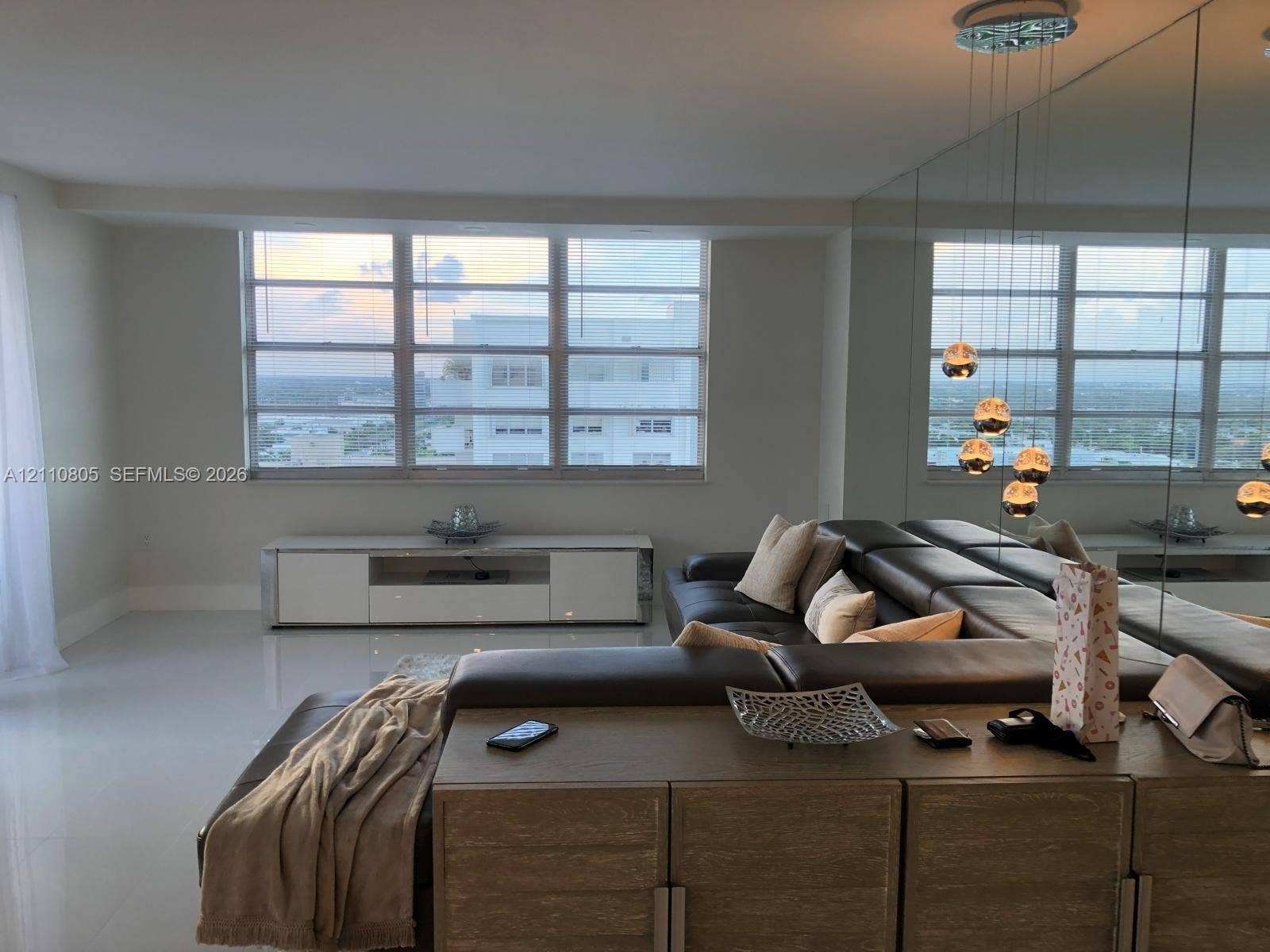 Large-format light-toned tile flooring, floor-to-ceiling wall mirror, multi-pane picture windows, and pendant globe lighting