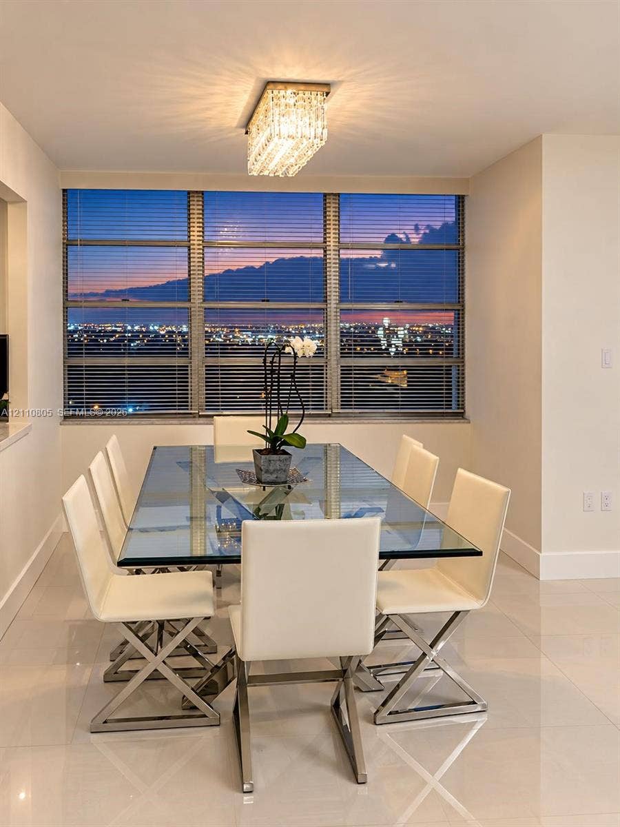 Large floor-to-ceiling windows featuring city-wide scenery, polished stone tile flooring, and a contemporary rectangular crystal-accented chandelier