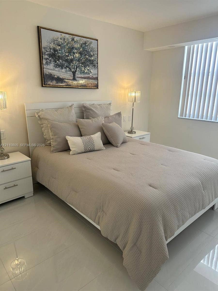 Neutral-toned tile flooring, recessed wall niche, and vertical window blinds