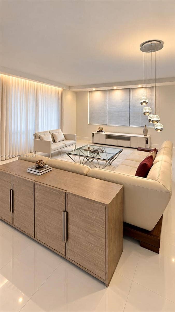 Living area featuring neutral-toned walls, high-gloss floor tile, recessed ceiling lighting, a modern multi-pendant light fixture, and built-in white cabinetry