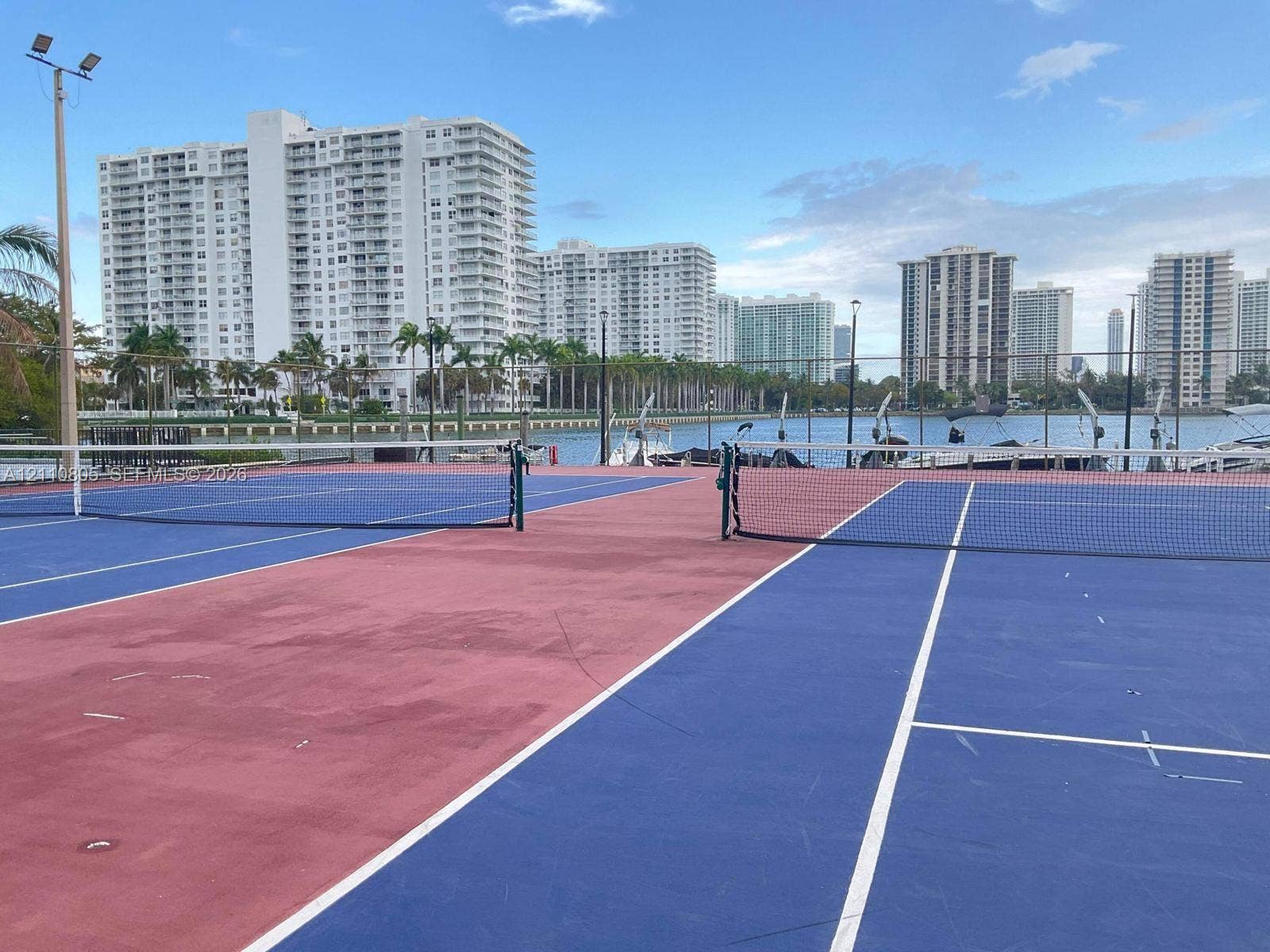 Multi-court tennis facility featuring high-tension netting, perimeter fencing, and pole-mounted floodlighting