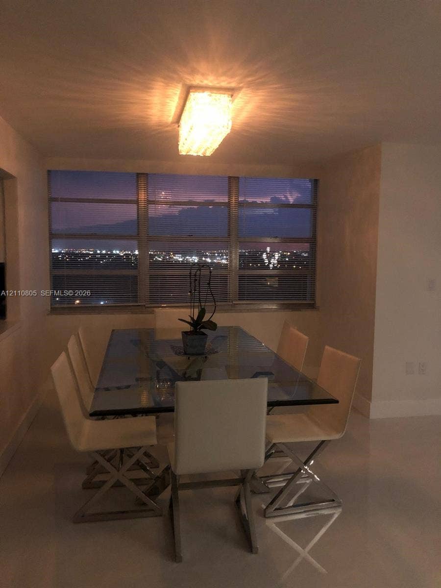 Expansive windows offering city landscape scenery, neutral flooring, and rectangular ceiling-mounted light fixture