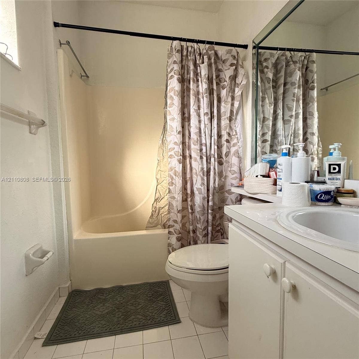 Bathroom featuring a white vanity cabinet with an integrated sink, a large wall-mounted mirror, and a tub-shower combination with a molded surround