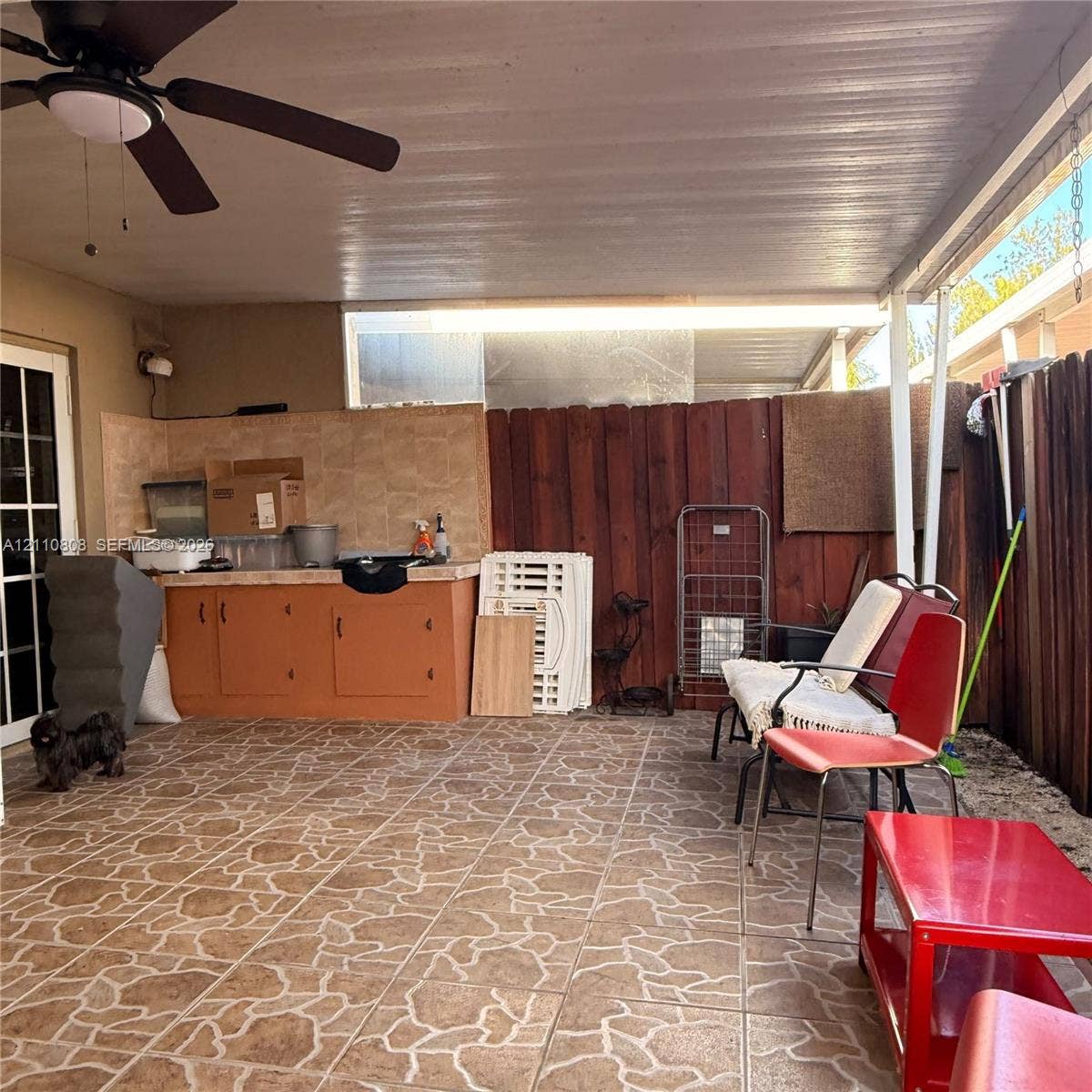 Covered outdoor patio featuring tiled flooring, built-in cabinetry with tiled backsplash, and an integrated ceiling fan