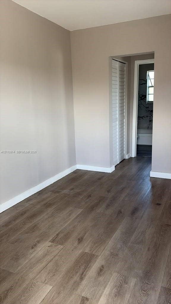 Neutral-toned interior walls featuring wood-finish flooring and a louvered bi-fold closet door