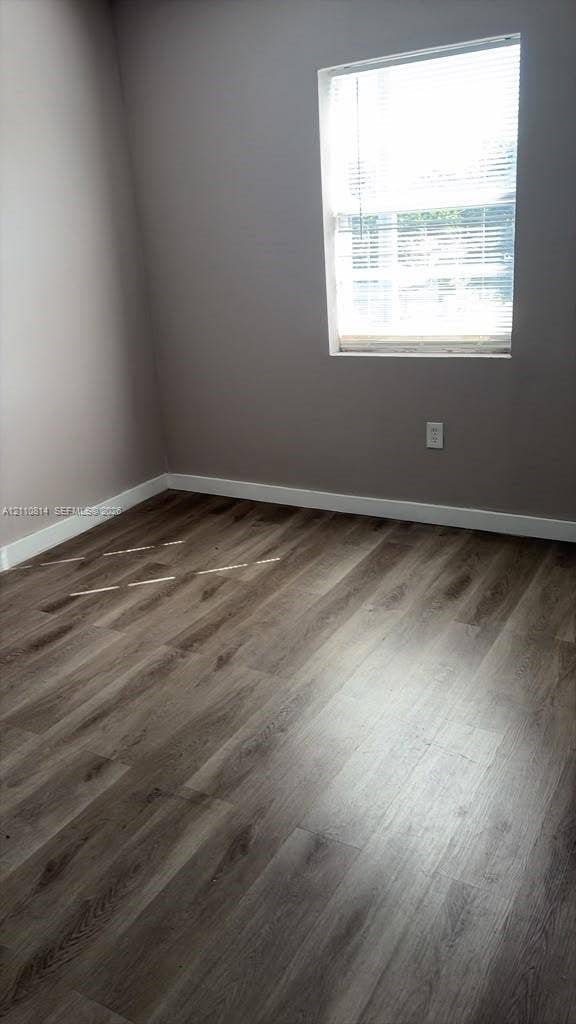 Room featuring neutral-toned walls, wood-finish flooring, and a single-pane window