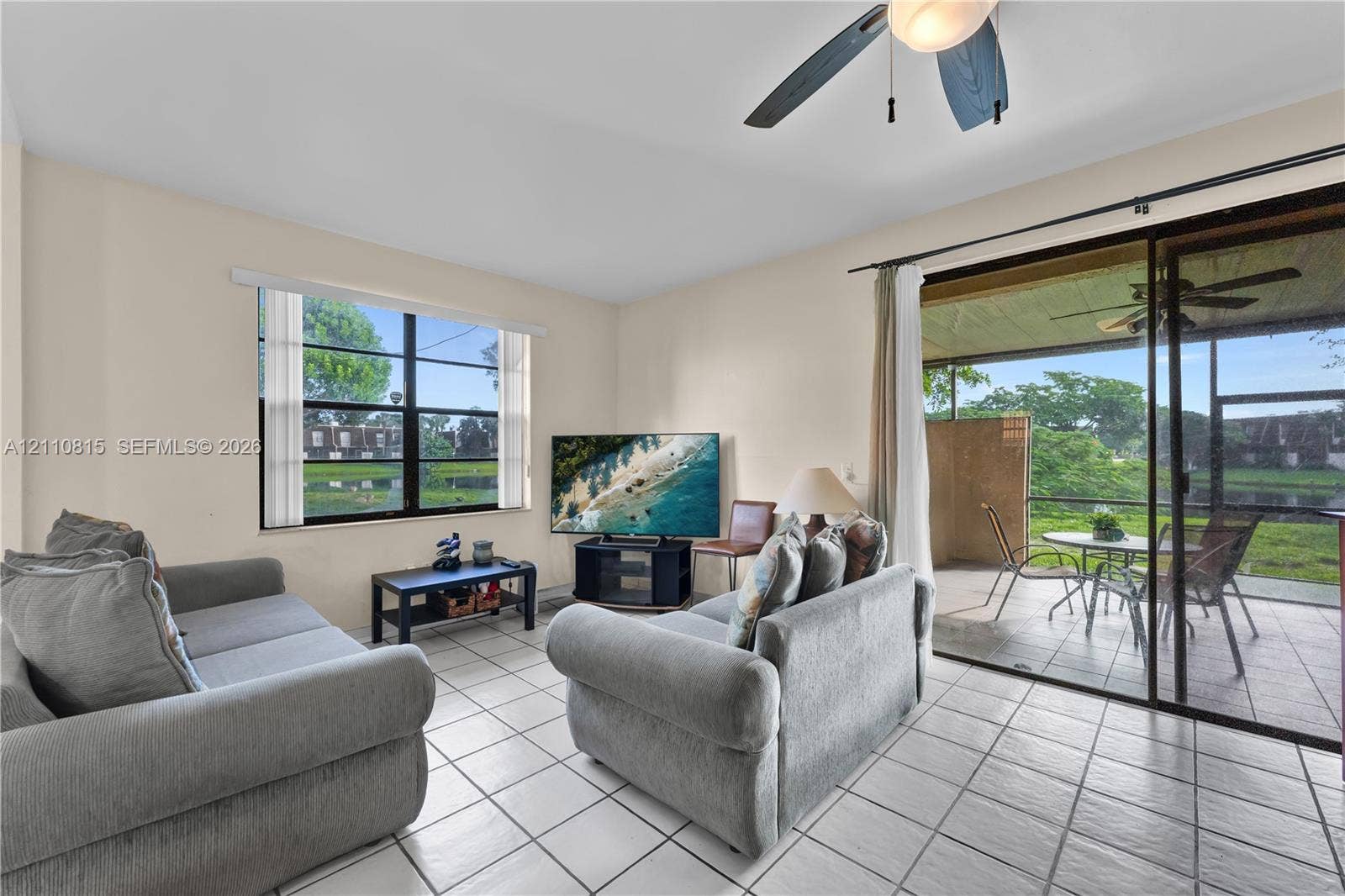 9100 Orchid Tree Lane, #137, Pembroke Pines, FL 33024 Living area featuring tile flooring, ceiling fan, large window, and sliding glass doors opening to a screened lanai