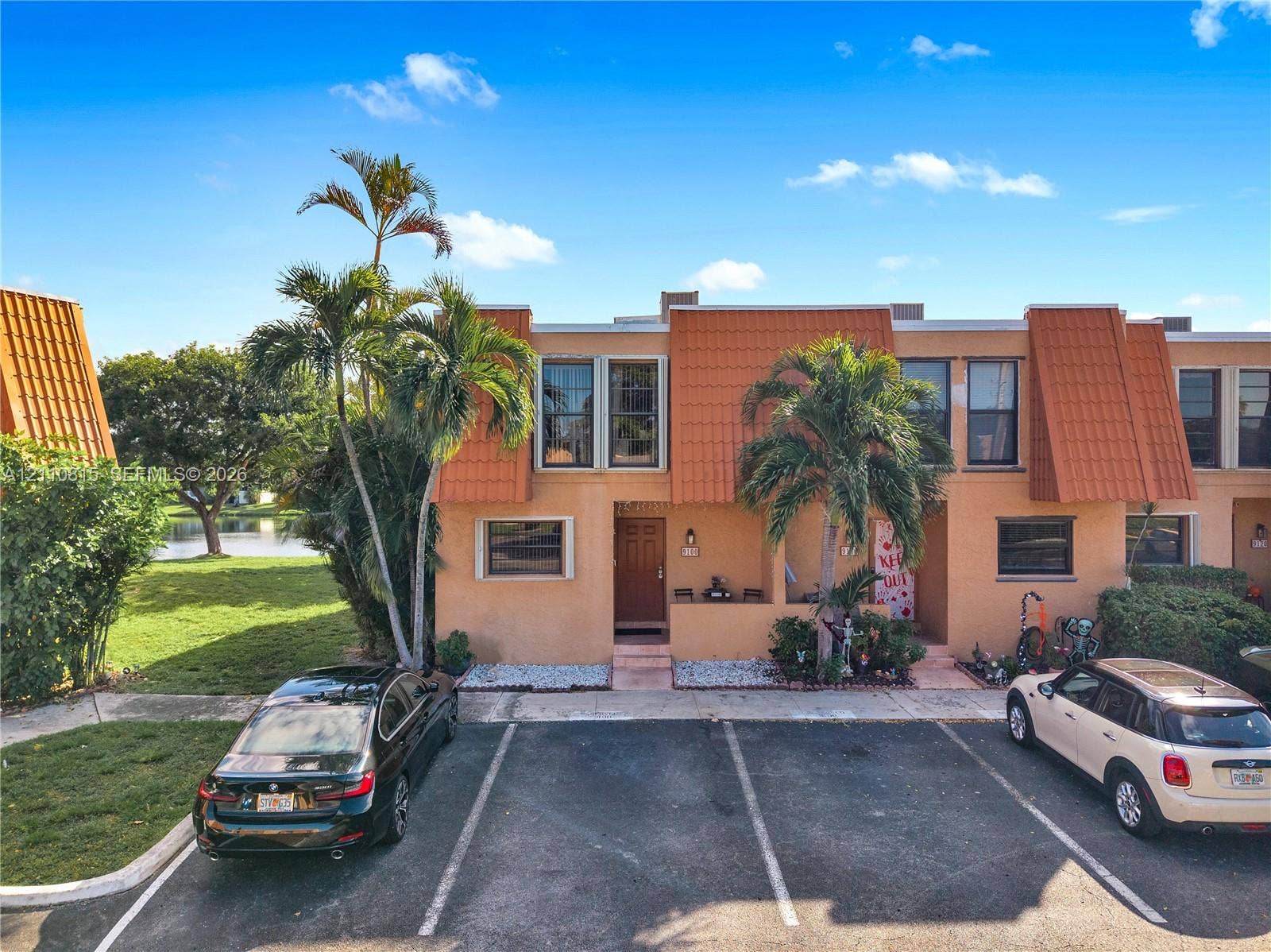 9100 Orchid Tree Lane, #137, Pembroke Pines, FL 33024 Two-story exterior featuring stucco siding, prominent mansard-style roof elements, dual assigned parking spaces, and mature palm trees