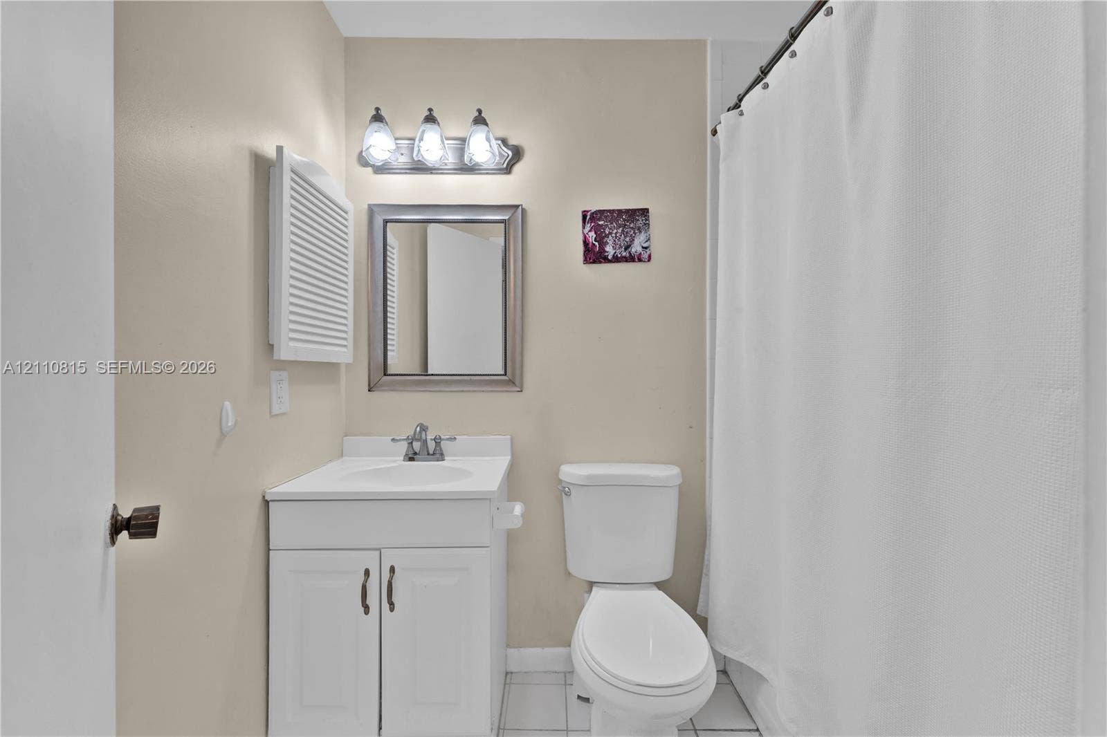 9100 Orchid Tree Lane, #137, Pembroke Pines, FL 33024 Bathroom featuring a white vanity cabinet with a stone-top integrated sink, a framed wall mirror, a three-light vanity fixture, and tiled flooring