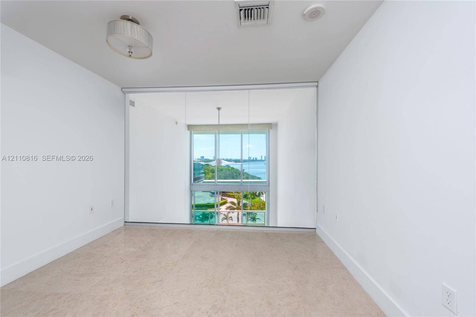Floor-to-ceiling mirror wall, neutral stone-finish flooring, and recessed drum ceiling light