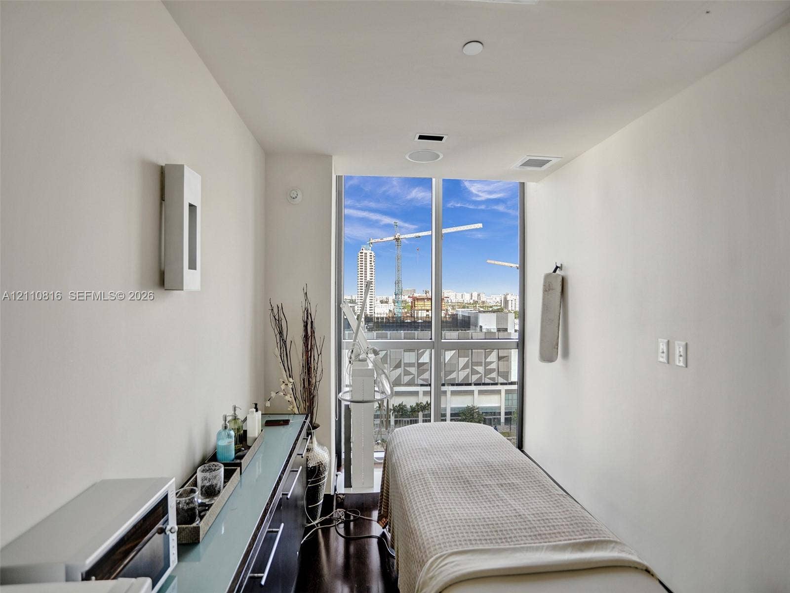 Floor-to-ceiling windows, dark wood-finish flooring, built-in cabinetry with a glass surface, recessed ceiling lighting, and wall-mounted sconce lighting