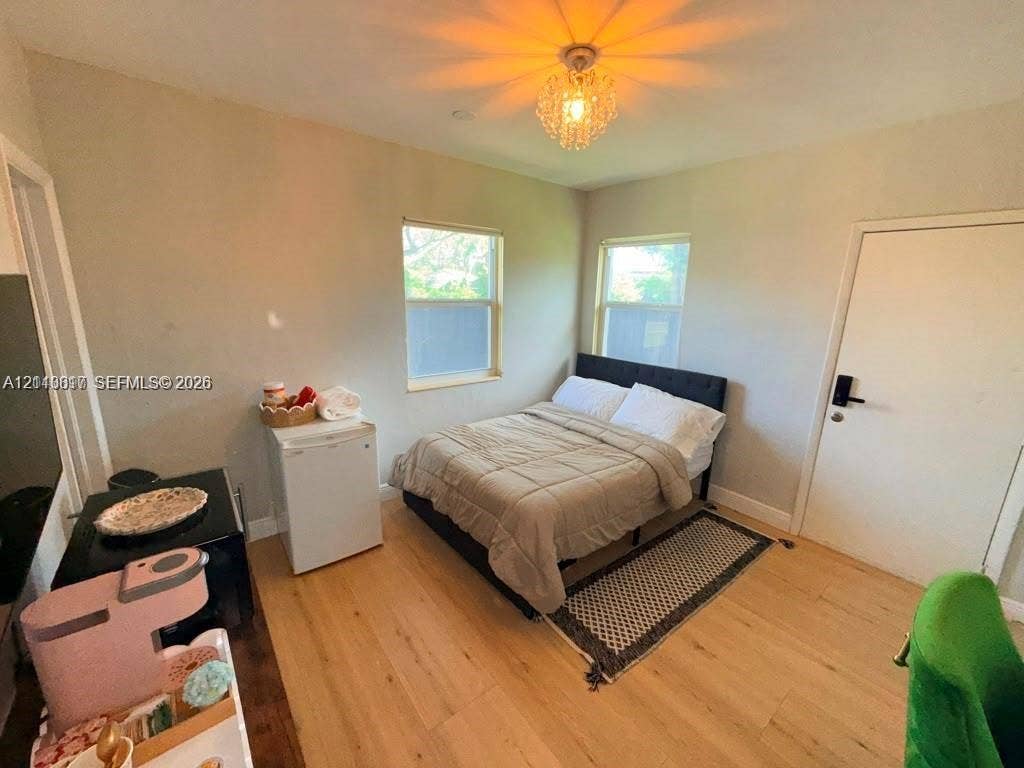 201 Flagler Drive, #201, Miami Springs, Miami Springs, FL 33166 Light-filled room featuring wood-finish flooring, two dual-pane windows, and a decorative crystal flush-mount light fixture