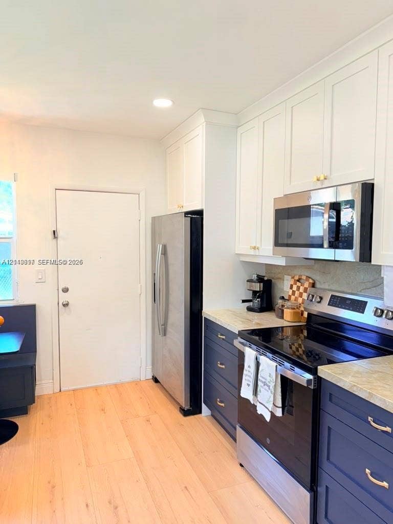 201 Flagler Drive, #201, Miami Springs, Miami Springs, FL 33166 Kitchen featuring two-tone shaker-style cabinetry, wood-finish flooring, stone-surfaced countertops, and stainless steel appliances