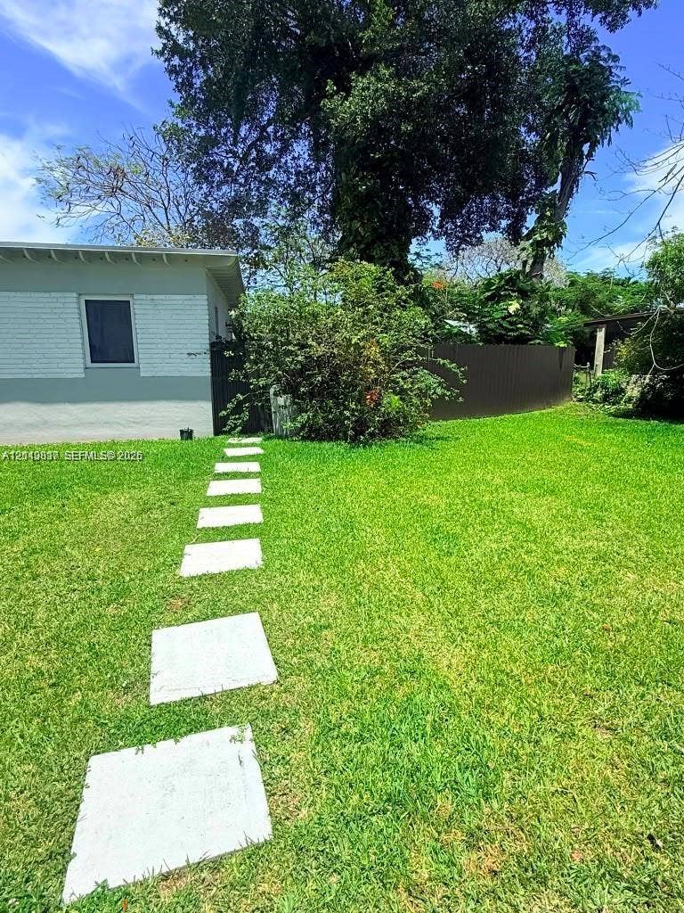 201 Flagler Drive, #201, Miami Springs, Miami Springs, FL 33166 Expansive backyard featuring a manicured lawn, stone paver pathway, privacy fencing, and mature trees