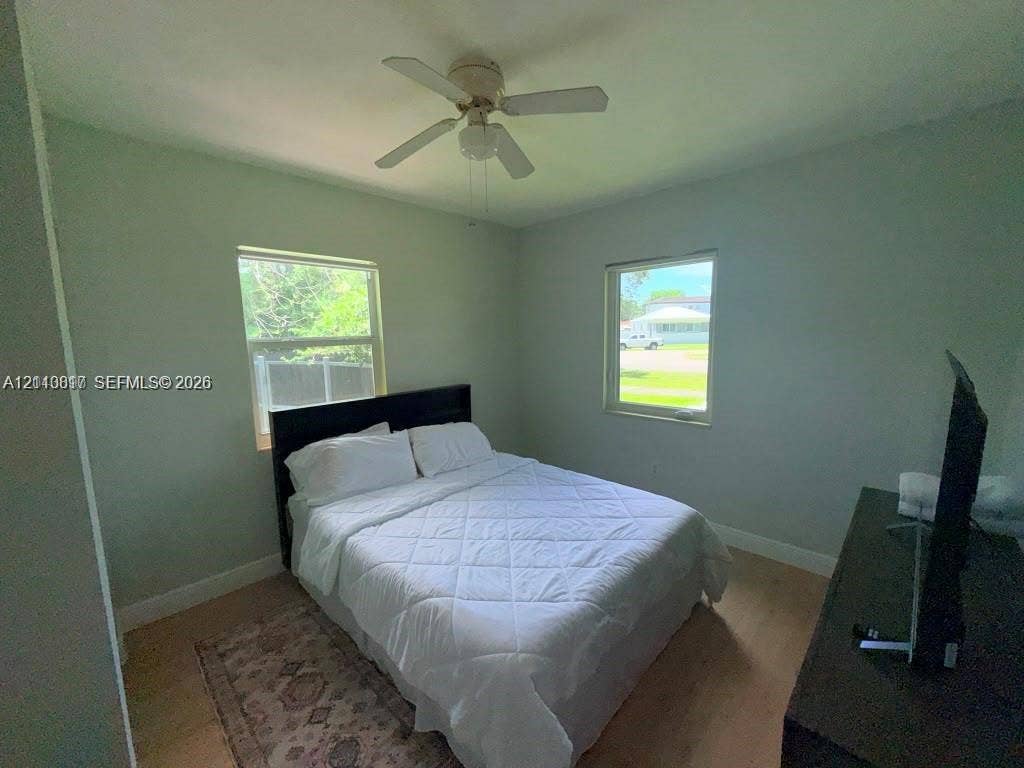 201 Flagler Drive, #201, Miami Springs, Miami Springs, FL 33166 Bedroom featuring light-toned wood-finish flooring, two large windows, and a central ceiling fan with integrated lighting