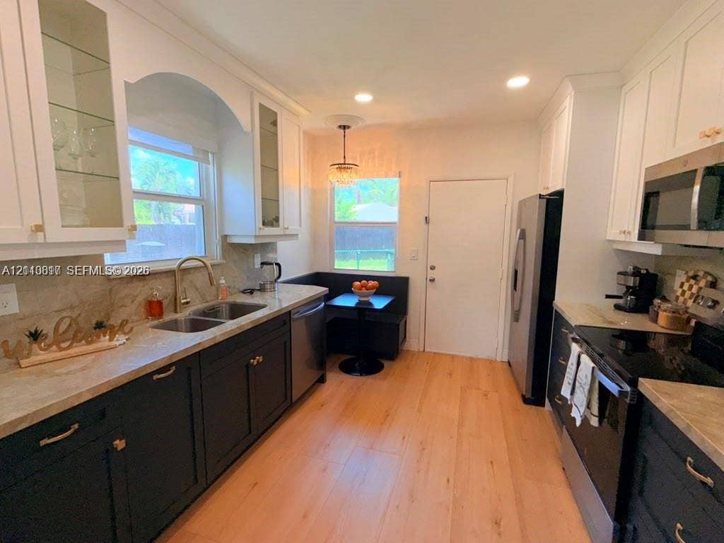 201 Flagler Drive, #201, Miami Springs, Miami Springs, FL 33166 Kitchen featuring white upper cabinetry, dark base cabinetry, wood-finish flooring, stone-surfaced countertops, and stainless steel appliances
