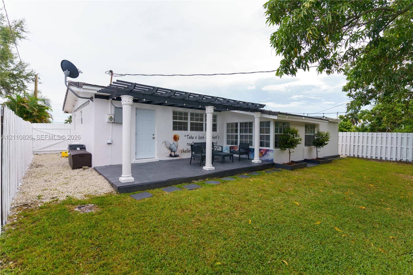 Exterior patio featuring a pergola with classic columns, concrete surfacing, fenced yard, and gravel side path