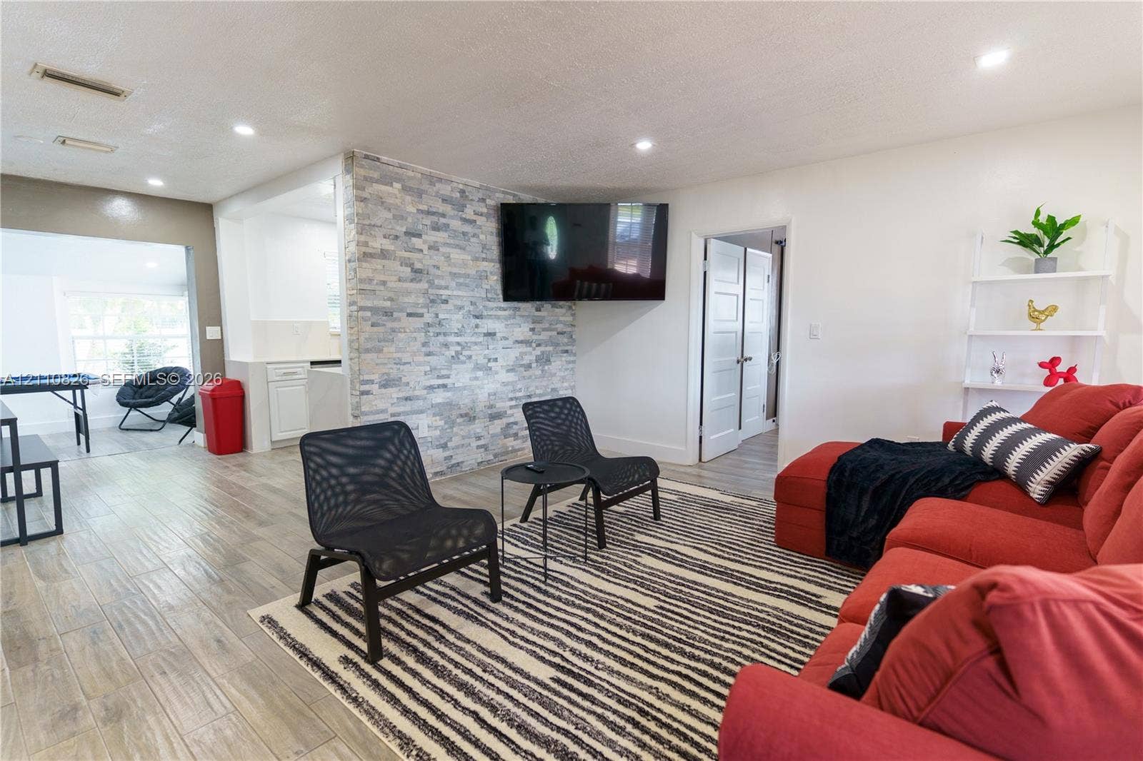 Living area featuring wood-finish flooring, a textured stone accent wall, and recessed lighting