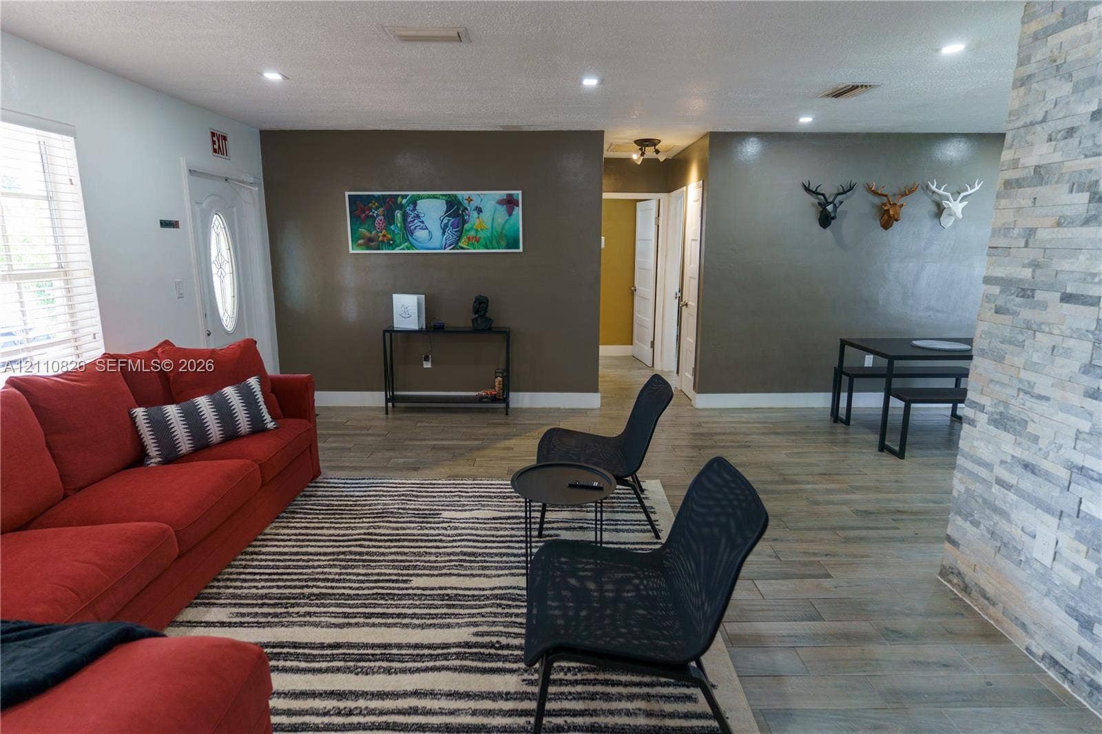 Open-concept area featuring stone-clad accent wall, recessed lighting, and wood-finish flooring