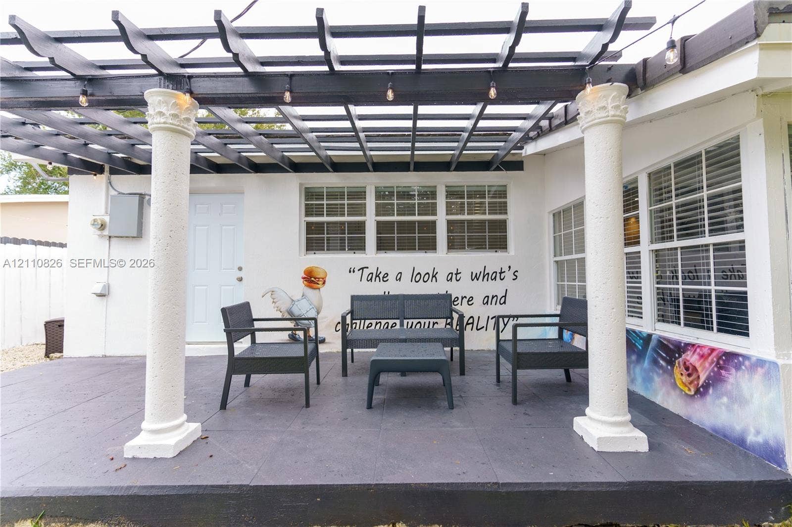 Covered patio featuring a dark-finish pergola, classic architectural columns, and multi-pane windows