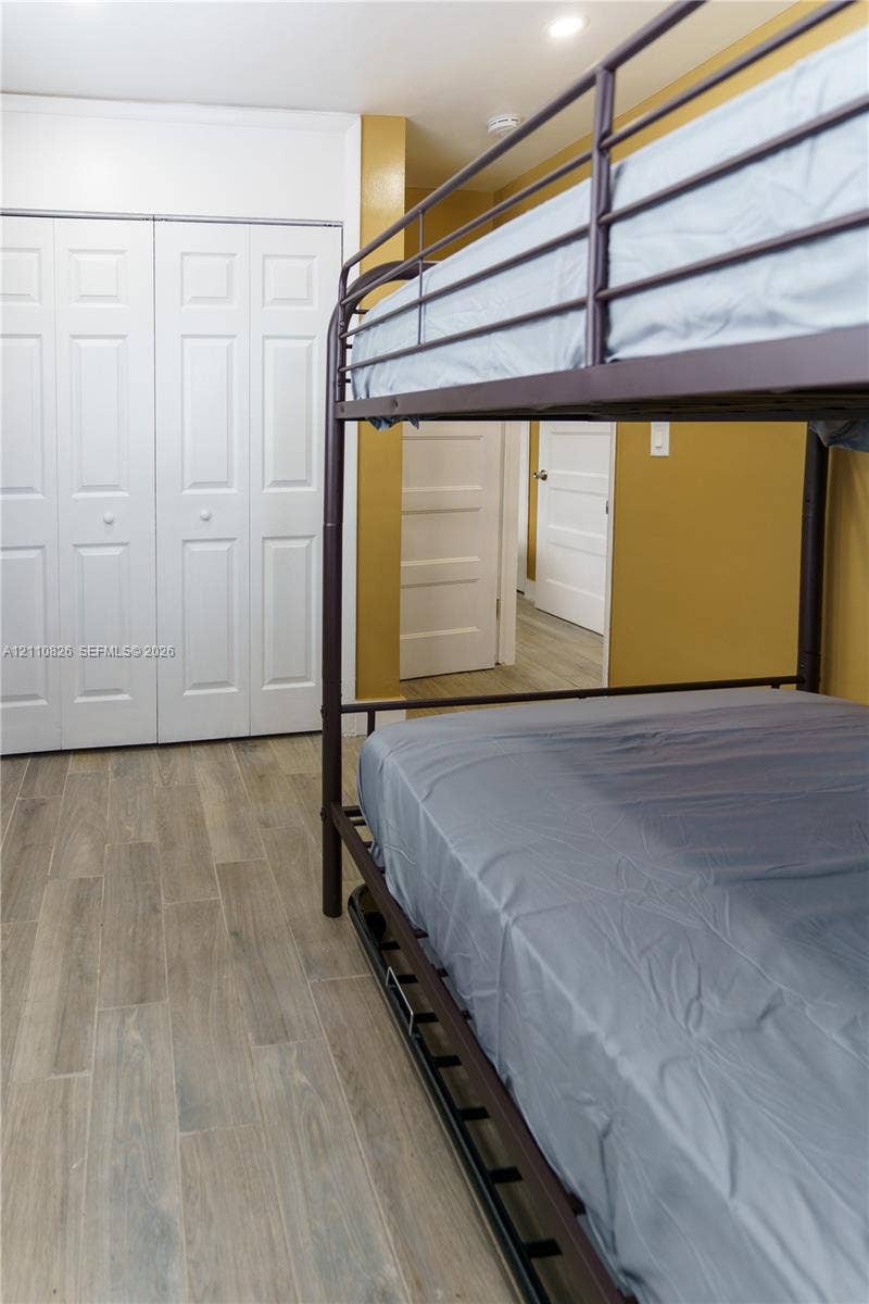 Wood-finish flooring, white bi-fold closet doors, and interior paneled doors