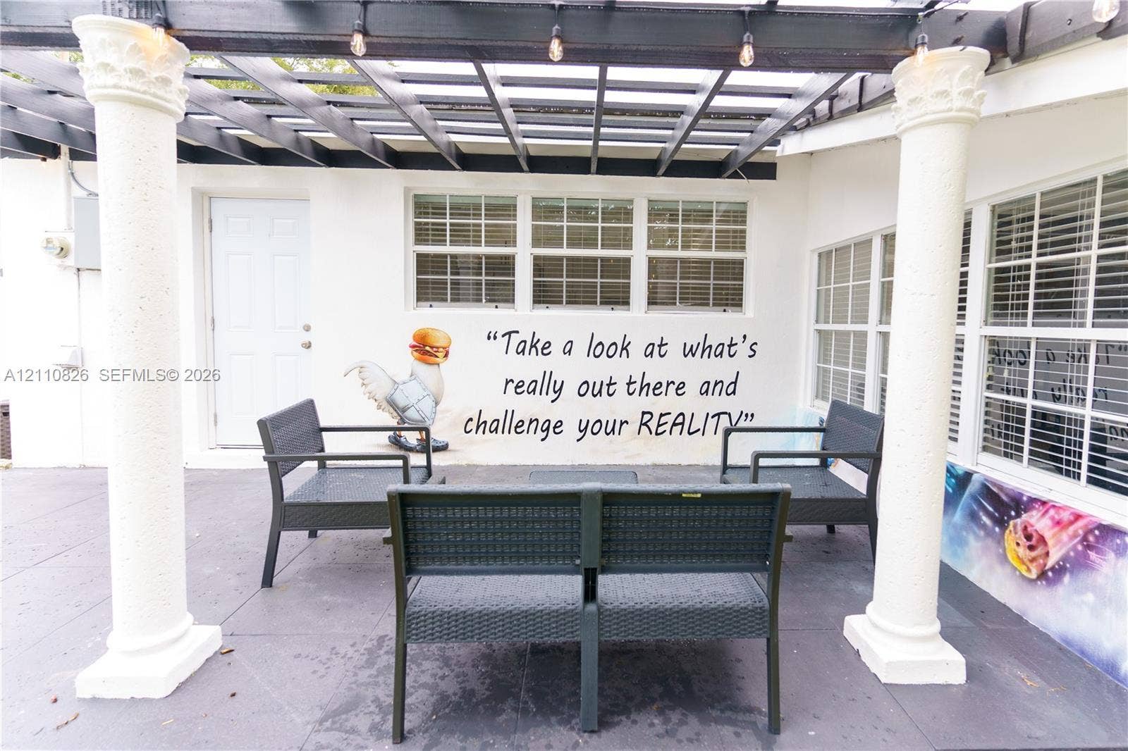 Patio area featuring a dark-toned pergola, decorative columns, and multi-pane windows