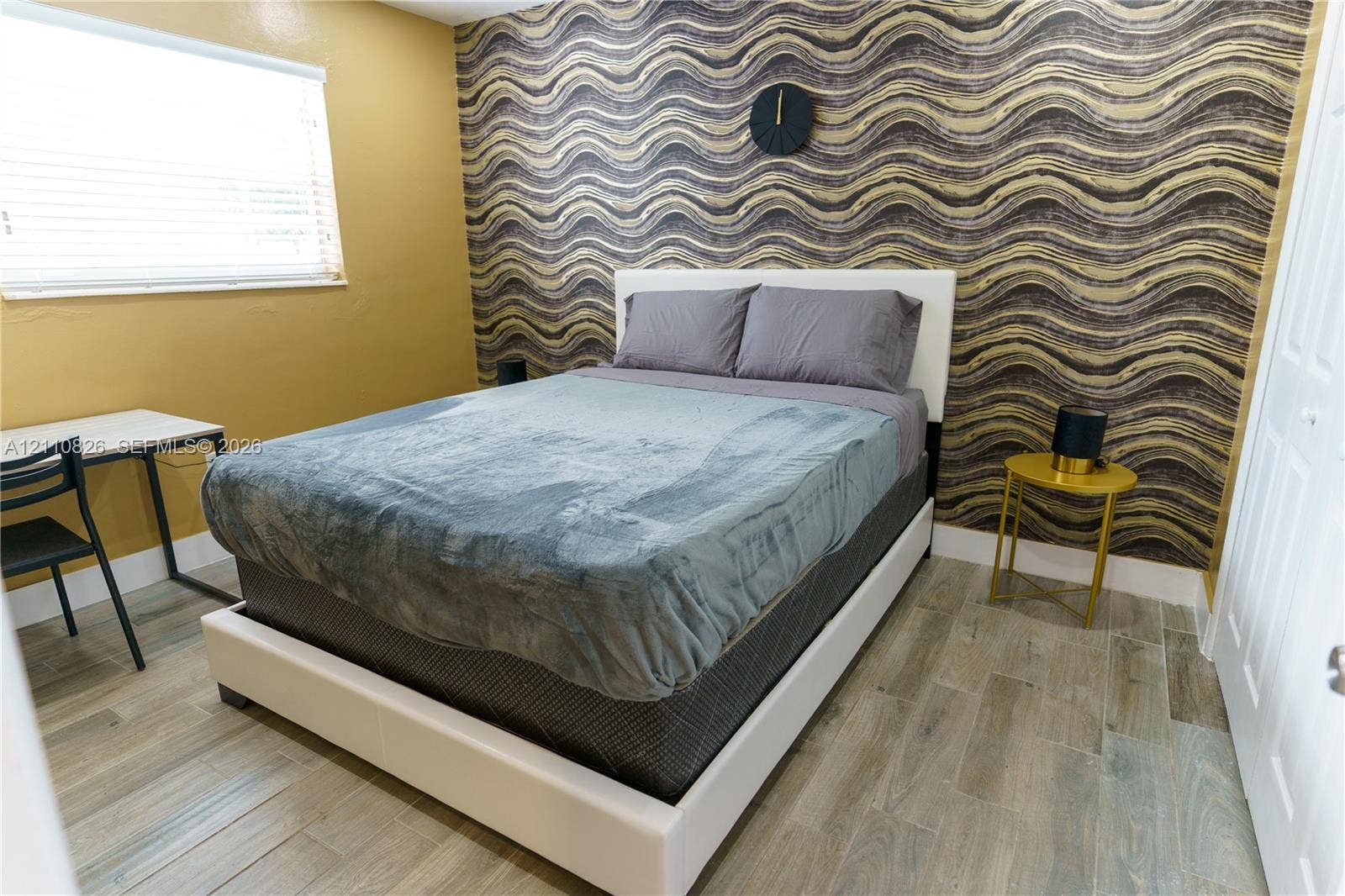 Room featuring patterned wall covering, wood-finish tile flooring, and a multi-panel door