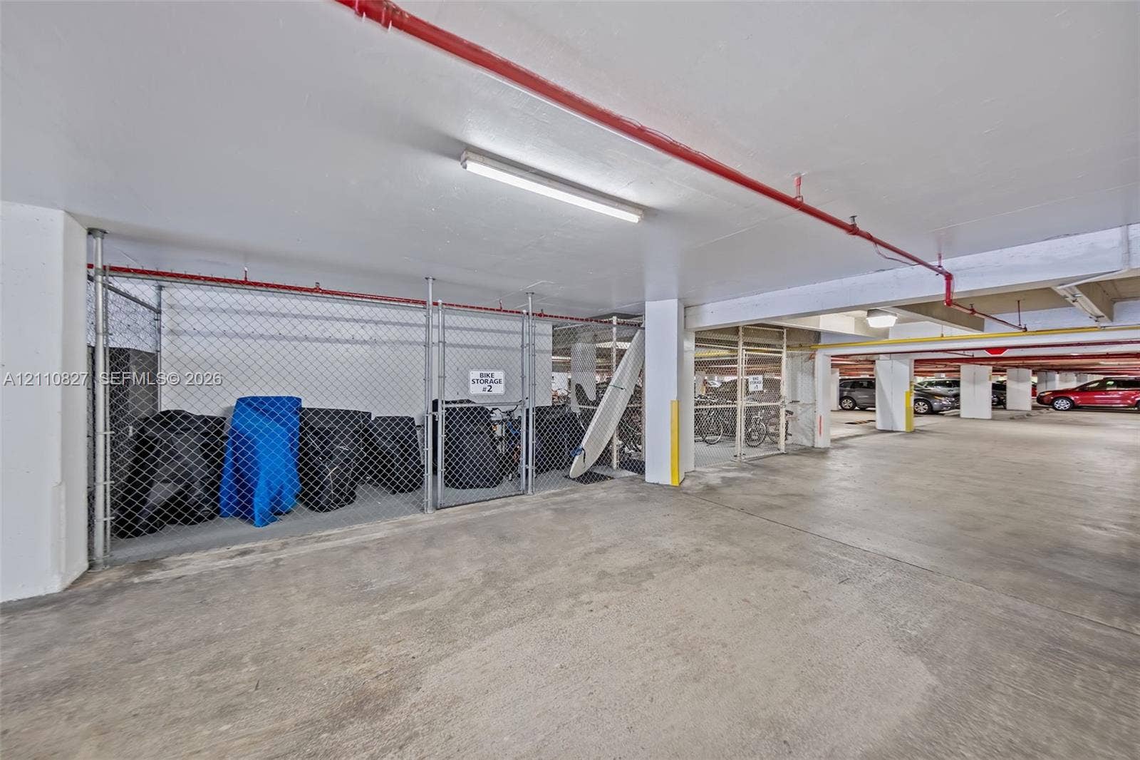 4000 Towerside Terrace, #908, Miami, Miami, FL 33138 Covered parking area featuring concrete flooring, chain-link storage lockers, and overhead lighting
