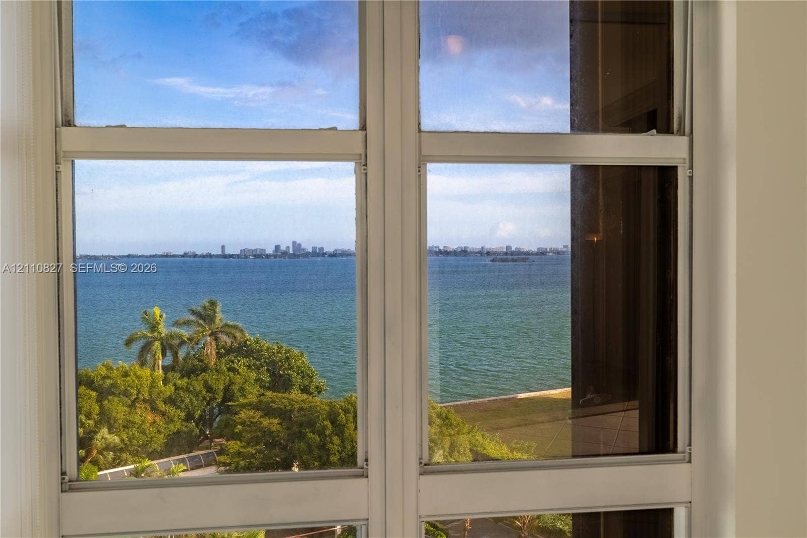 4000 Towerside Terrace, #908, Miami, Miami, FL 33138 Double-pane window featuring a white frame, offering expansive water scenery, mature palm trees, and a distant cityscape horizon