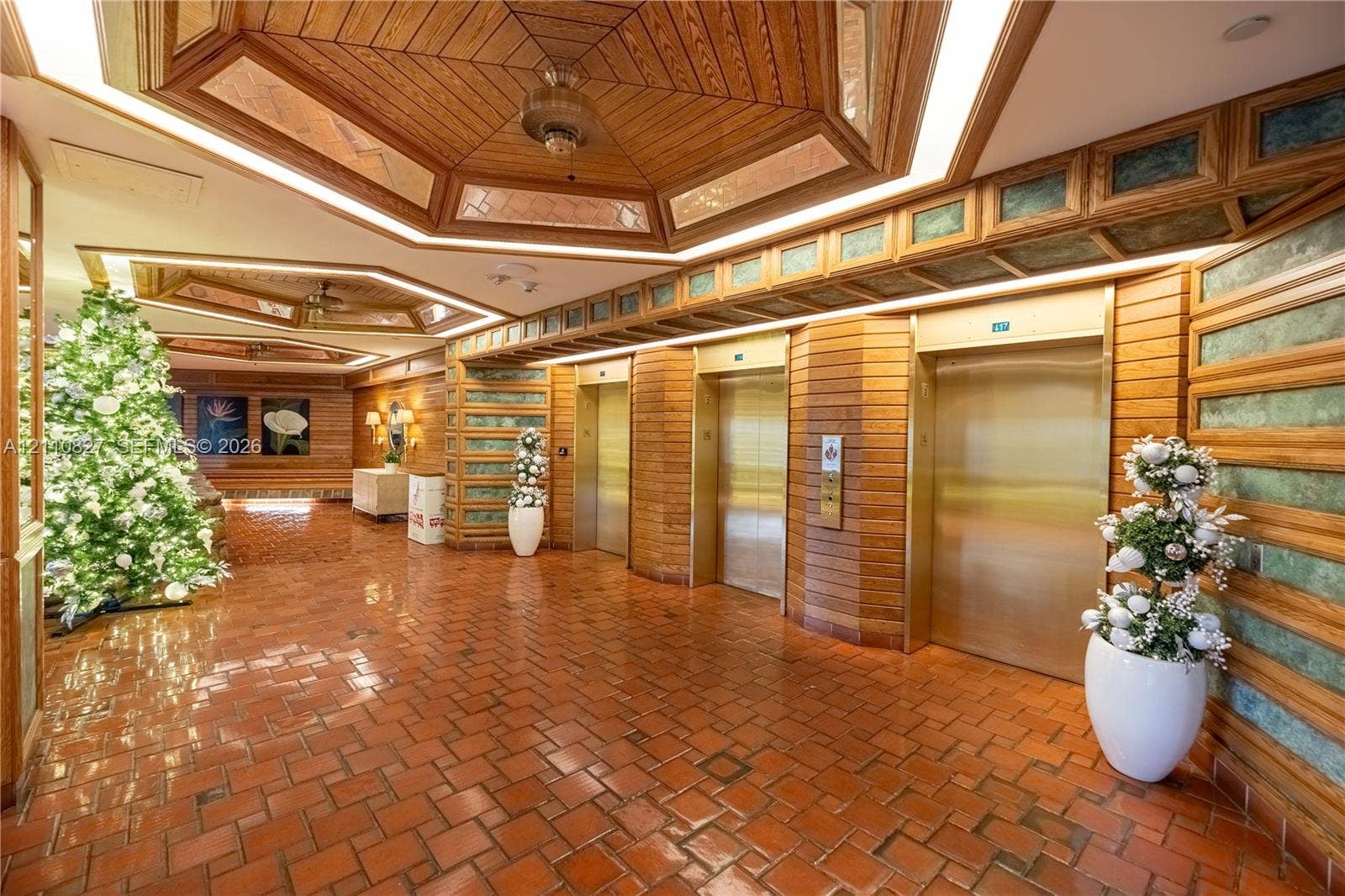 4000 Towerside Terrace, #908, Miami, Miami, FL 33138 Lobby entrance featuring hexagonal wood-paneled ceilings with recessed accent lighting, metallic-finish elevator doors, and horizontal wood wall paneling with inset tile detailing over terracotta flooring