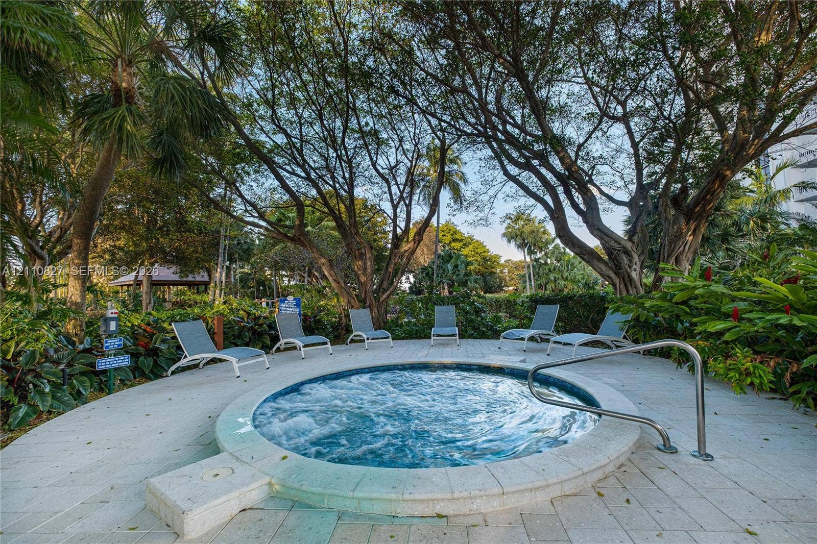4000 Towerside Terrace, #908, Miami, Miami, FL 33138 In-ground circular spa featuring a stone paver deck, stainless steel handrail, and mature tropical landscaping